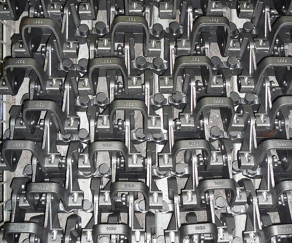 A rack of identical near-net-shape steel parts after closed-die forging and machining