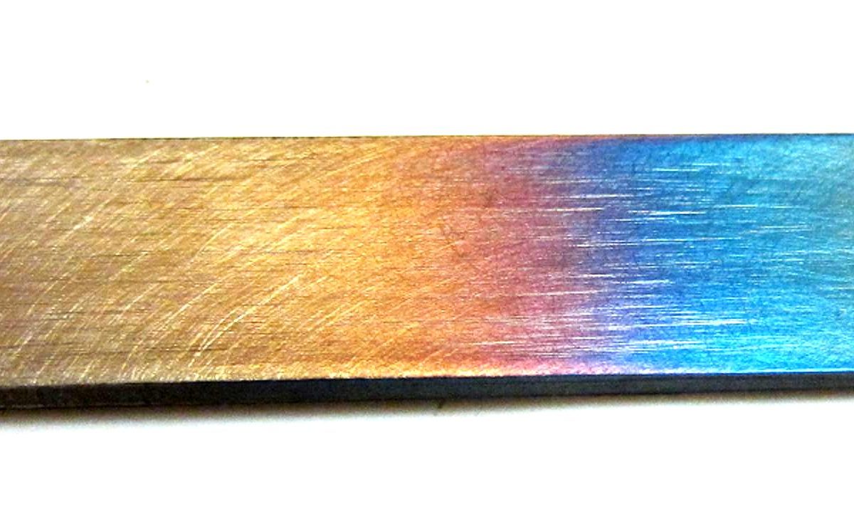 Temper colors — a spectrum from straw to blue — on a steel bar surface after controlled tempering