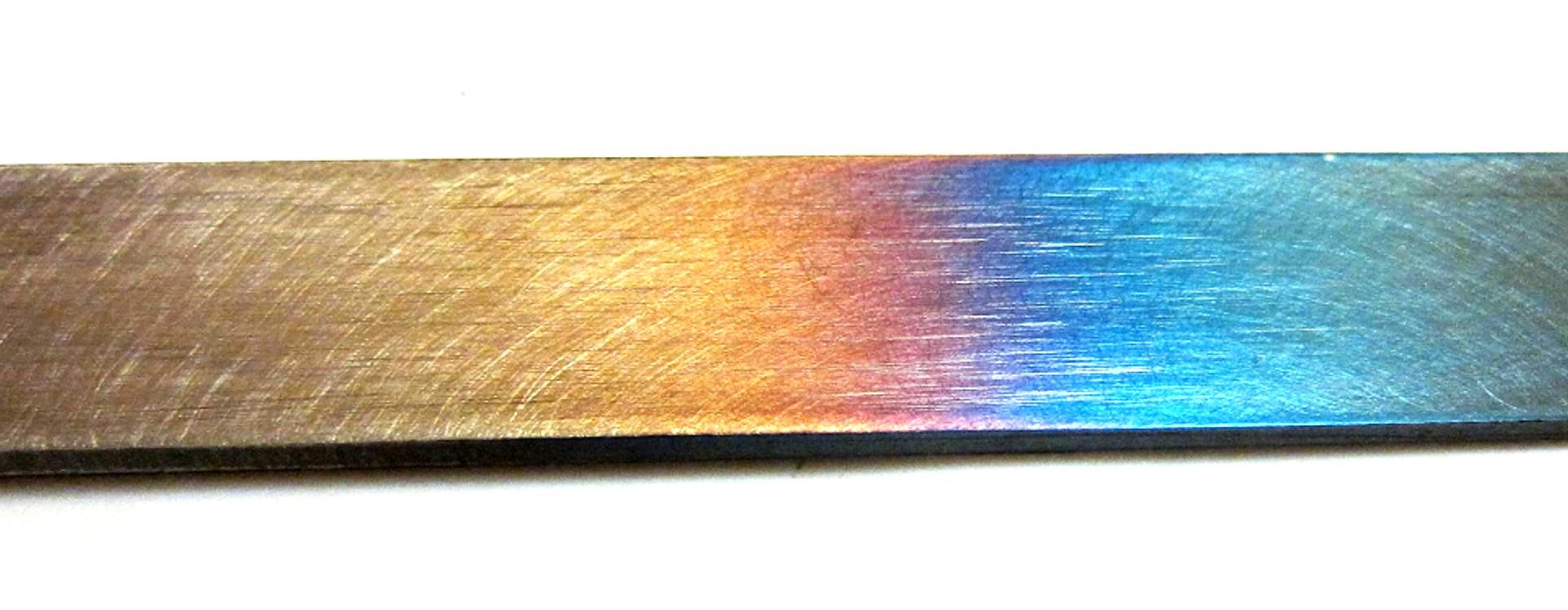 Temper colors — a spectrum from straw to blue — on a steel bar surface after controlled tempering